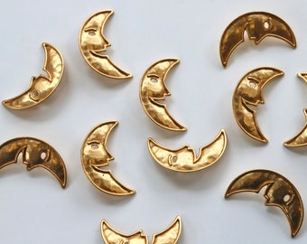 Puede incluir: Una colección de 10 dijes de metal dorado en forma de media luna con un diseño de cara sonriente. Los dijes tienen una textura martillada y son perfectos para la elaboración de joyas o manualidades.