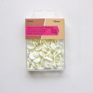 K&ouml;nnte beinhalten: Eine Packung mit 30 wei&szlig;en Kunststoff-Druckkn&ouml;pfen, 12 mm gro&szlig;. Die Verpackung ist mit "Boutons Pression Plastique" und "Mediac" beschriftet.