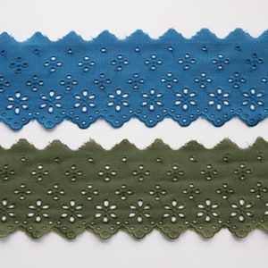 May include: Two pieces of scalloped cotton lace trim with a floral pattern. The top piece is teal blue and the bottom piece is olive green.