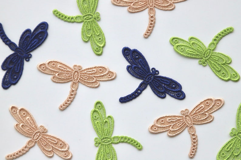 May include: Assortment of delicate lace dragonfly embellishments in green, beige, and blue. These decorative accents are perfect for adding a touch of whimsy to crafts, clothing, and home decor.