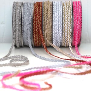 May include: A collection of seven spools of decorative trim with scalloped edges. The trim is available in silver, gold, white, pink, and red.