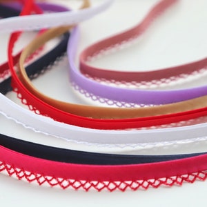 May include: Assortment of colorful elastic trim with a delicate lace edging. The trim is available in red, white, black, purple, brown, and pink.