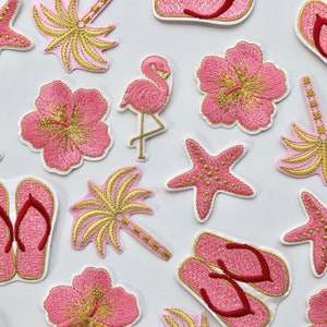 May include: A collection of pink and gold embroidered iron-on patches featuring tropical themes, including palm trees, hibiscus flowers, flamingos, and starfish.
