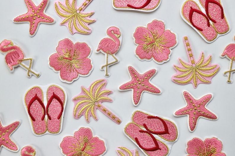 Puede incluir: Una colecci&oacute;n de parches de planchado bordados en rosa y dorado con temas tropicales, incluyendo palmeras, flores de hibisco, flamencos y estrellas de mar.
