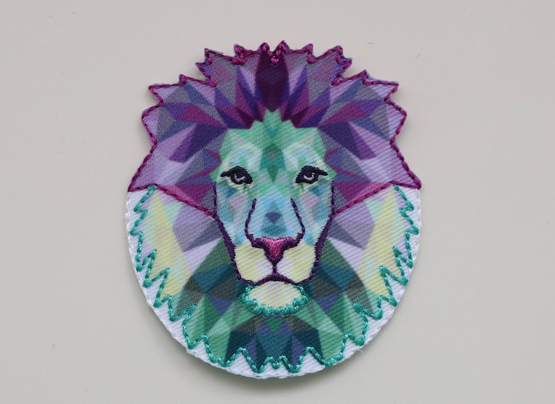 May include: A colorful geometric lion head patch with a purple, green, and blue color scheme. The patch is embroidered with a white outline.