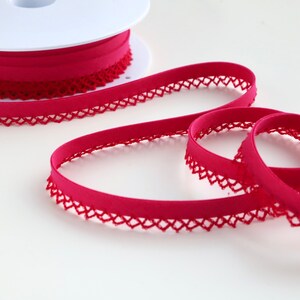 May include: A spool of bright pink elastic trim with a delicate lace edge. The trim is soft and stretchy, perfect for adding a touch of elegance to any project.