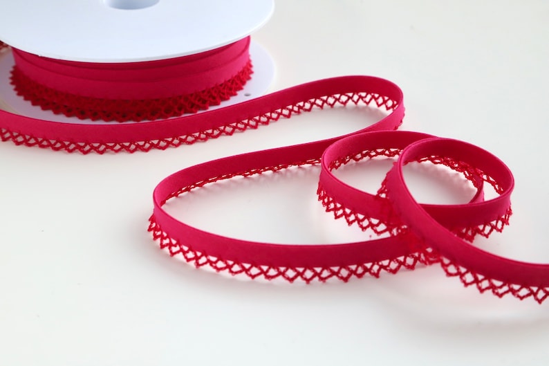 May include: A spool of bright pink elastic trim with a delicate lace edge. The trim is soft and stretchy, perfect for adding a touch of elegance to any project.