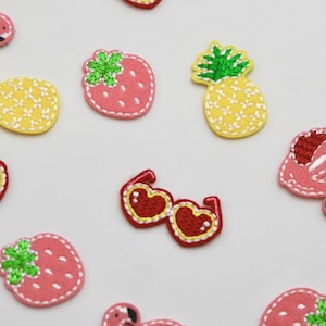 May include: Assortment of colourful iron-on patches featuring a pineapple, strawberry, flamingo, and sunglasses. The patches are perfect for adding a fun and whimsical touch to clothing, bags, or other accessories.
