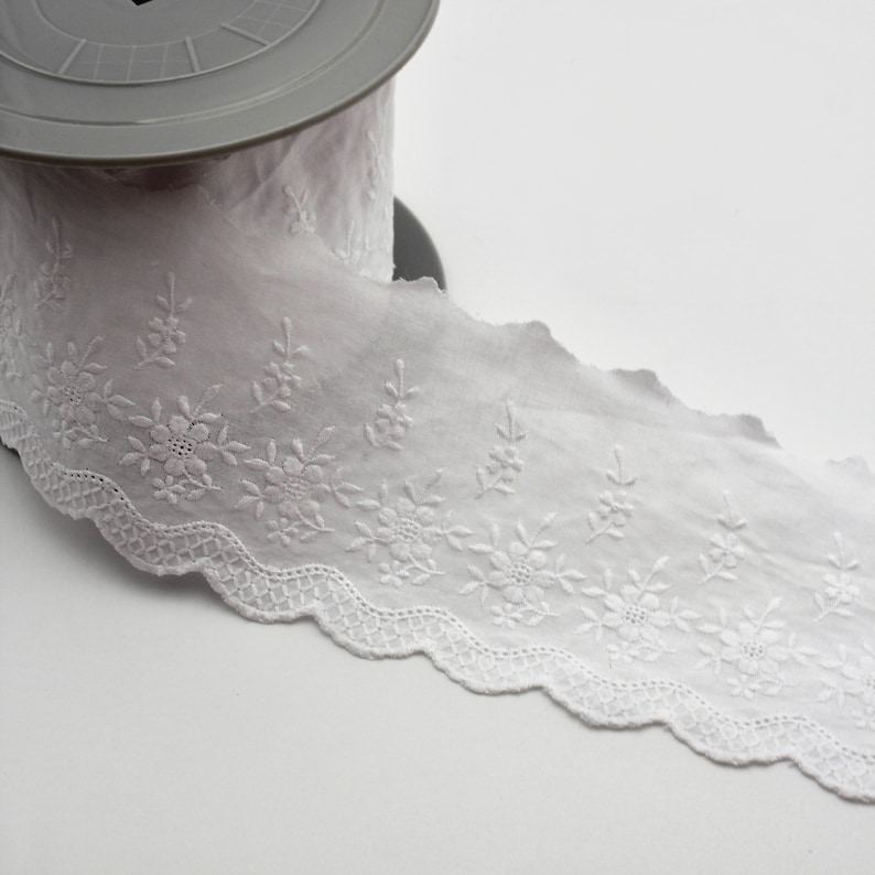 Peut inclure: Galon de dentelle en coton blanc avec un bord festonn&eacute; et un motif floral brod&eacute;.
