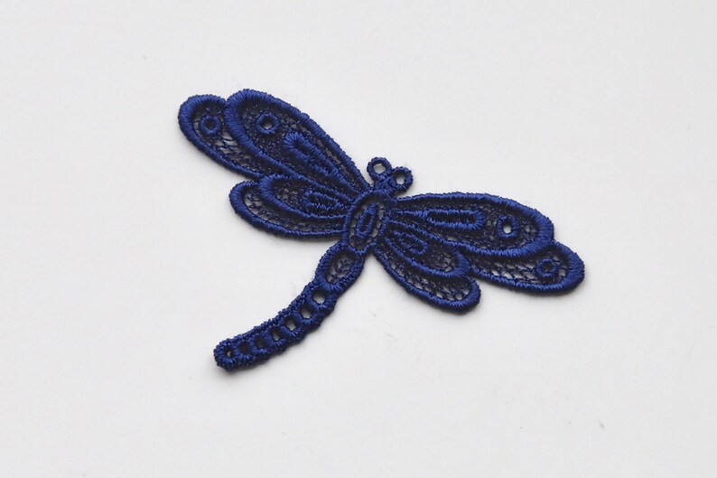 May include: A navy blue lace dragonfly applique. This delicate design is perfect for adding a touch of whimsy to crafts and sewing projects.