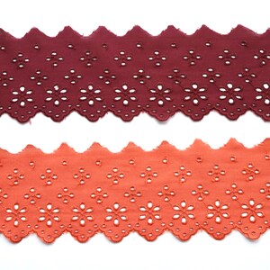 May include: Two pieces of brown and orange cotton lace trim with a scalloped edge and a floral pattern.