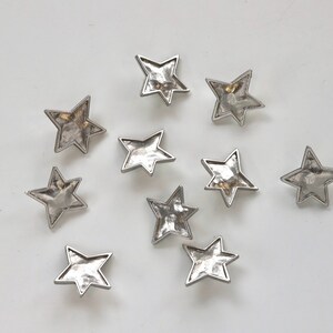 Puede incluir: Diez adornos de metal en forma de estrella plateados con textura martillada.