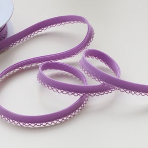 May include: A spool of purple elastic trim with a delicate lace edge. The trim is soft and stretchy, perfect for adding a touch of elegance to sewing projects.