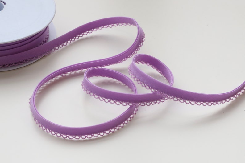 May include: A spool of purple elastic trim with a delicate lace edge. The trim is soft and stretchy, perfect for adding a touch of elegance to sewing projects.