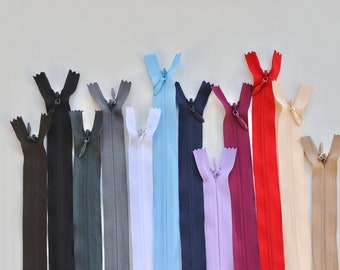 May include: Assortment of 12 zipper closures in various colours, including black, grey, white, light blue, navy blue, lavender, burgundy, red, beige, and brown.