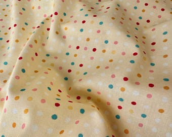May include: A yellow fabric with a polka dot pattern. The dots are in various colours, including red, orange, teal, and white.