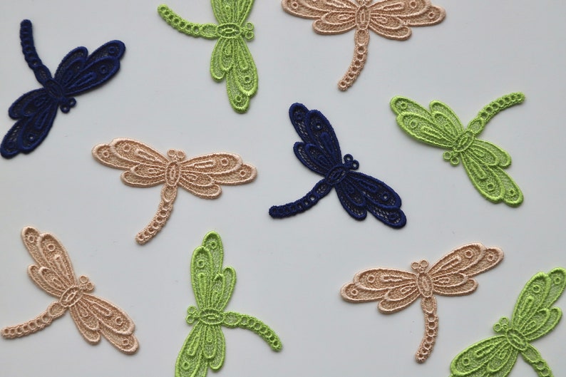 May include: Assortment of delicate dragonfly lace appliques in green, beige, and navy blue. These intricate designs are perfect for adding a touch of whimsy to crafts and sewing projects.