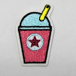 May include: An embroidered iron-on patch of a pink slushie cup with a yellow straw and a red star on the side.