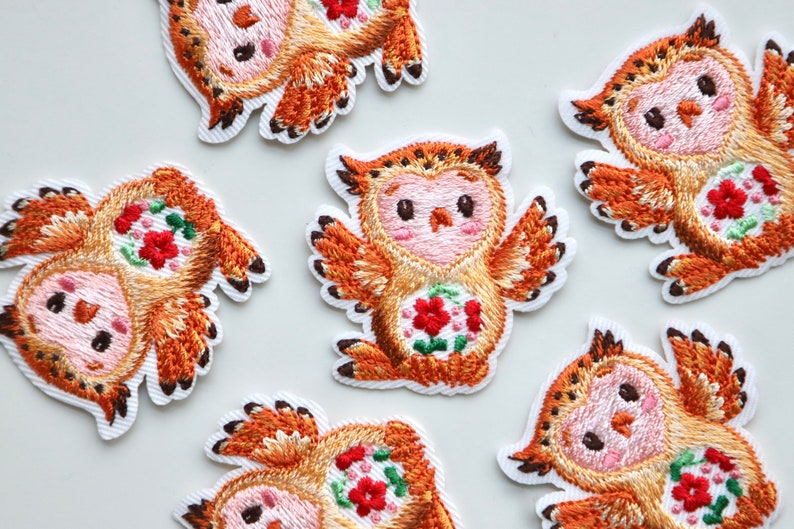 May include: Six embroidered iron-on patches featuring a cartoon owl with a floral design in shades of orange, pink, and white.