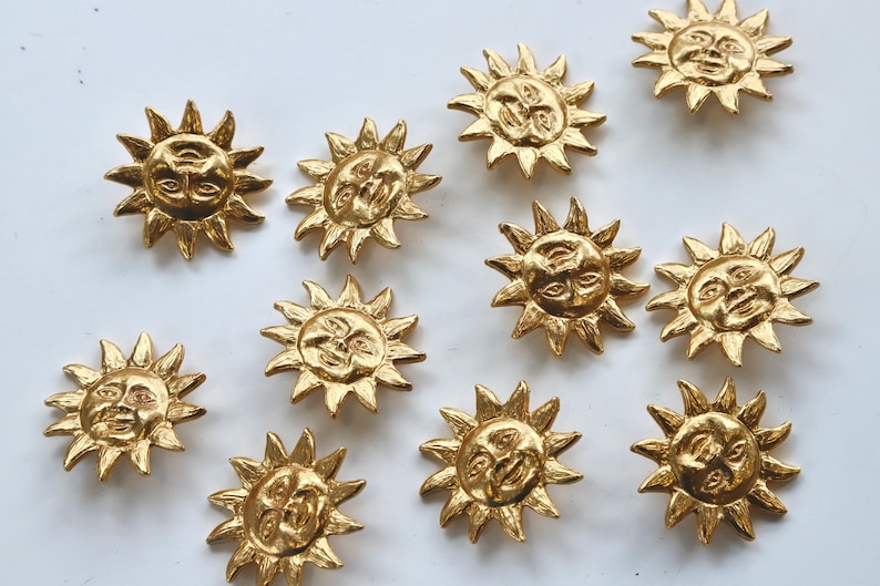 Puede incluir: Doce botones dorados en forma de sol con un dise&ntilde;o de cara. Cada bot&oacute;n tiene una cara en relieve con dos ojos, una nariz y una boca.