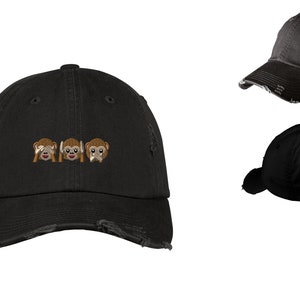 Può includere: Cappellino da baseball nero consumato con un'immagine ricamata di tre scimmie, una si copre gli occhi, una si copre le orecchie e una si copre la bocca. Le scimmie sono marroni con il viso bianco.