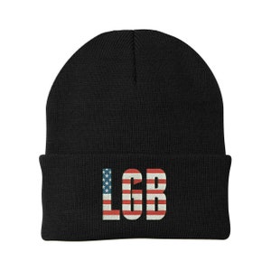 Puede incluir: Gorro de punto negro con las letras "LGB" en blanco con un diseño de bandera estadounidense.