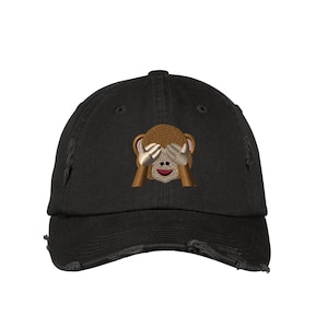 Può includere: Un cappello da baseball nero consumato con un'immagine ricamata di una scimmia che si copre gli occhi. La scimmia è marrone con la faccia gialla.