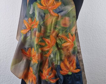 May include: A silk scarf with a floral design. The scarf is a dark blue color with a brown border. The flowers are orange and yellow and are arranged in a random pattern.