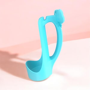 Puede incluir: Un cuchar&oacute;n azul claro con un mango curvo y un cuenco peque&ntilde;o y redondeado. El mango presenta un elemento decorativo en forma de nube en la parte superior. El cuchar&oacute;n est&aacute; hecho de un material liso y se encuentra sobre un fondo rosa.