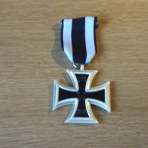 Puede incluir: Una medalla de la Cruz de Hierro de plata con un centro de esmalte negro y la inscripción "1914-1918" colgada de una cinta blanca y negra.