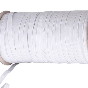 May include: A spool of white elastic cord, wound tightly on a cardboard core. The elastic is thin and flexible, perfect for sewing projects.