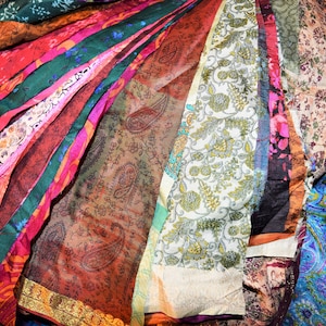 May include: A collection of colorful fabric scraps with various patterns, including paisley, floral, and geometric designs. The fabric is arranged in a fan shape, with the edges of the fabric overlapping.