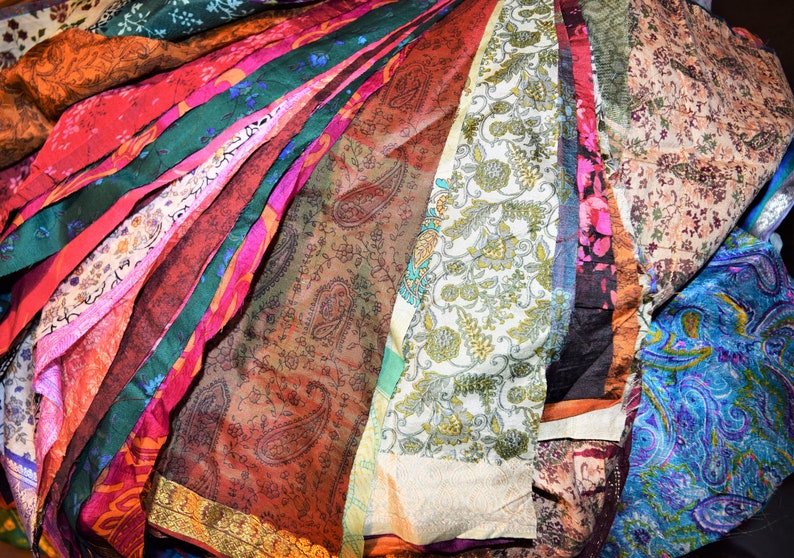May include: A collection of colorful fabric scraps with various patterns, including paisley, floral, and geometric designs. The fabric is arranged in a fan shape, with the edges of the fabric overlapping.
