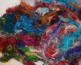 May include: A pile of colorful, tangled yarn scraps in shades of blue, red, green, white, and brown.