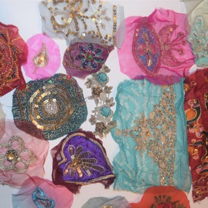 May include: A collection of colorful fabric patches with intricate embroidery and sequin embellishments. The patches feature various shapes and designs, including floral patterns and circular motifs. Colors include pink, teal, purple, and gold.