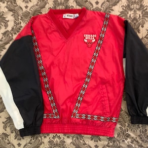 May include: Red, black, and white windbreaker jacket with a Chicago Bulls logo and a decorative trim. The jacket has a zipper closure and a v-neck.