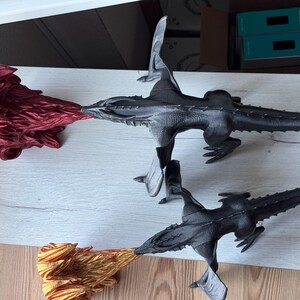 May include: Three black dragon figurines with wings, one with red flames, one with gold flames, and one with no flames.