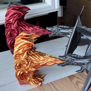 May include: Three 3D printed dragon figurines. One is red, one is gold, and one is black. The dragons are posed in a fighting stance.