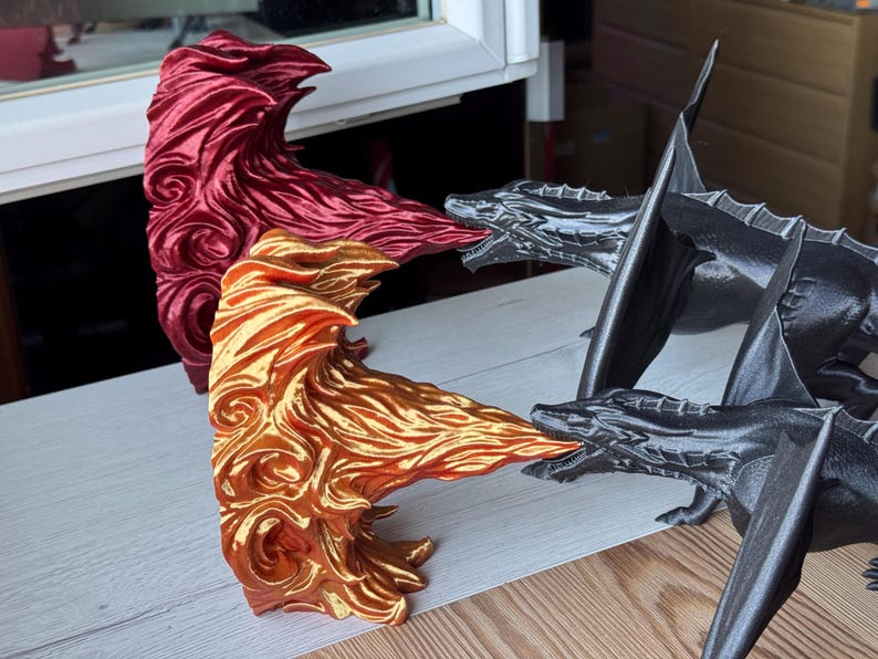 May include: Three 3D printed dragon figurines. One is red, one is gold, and one is black. The dragons are posed in a fighting stance.