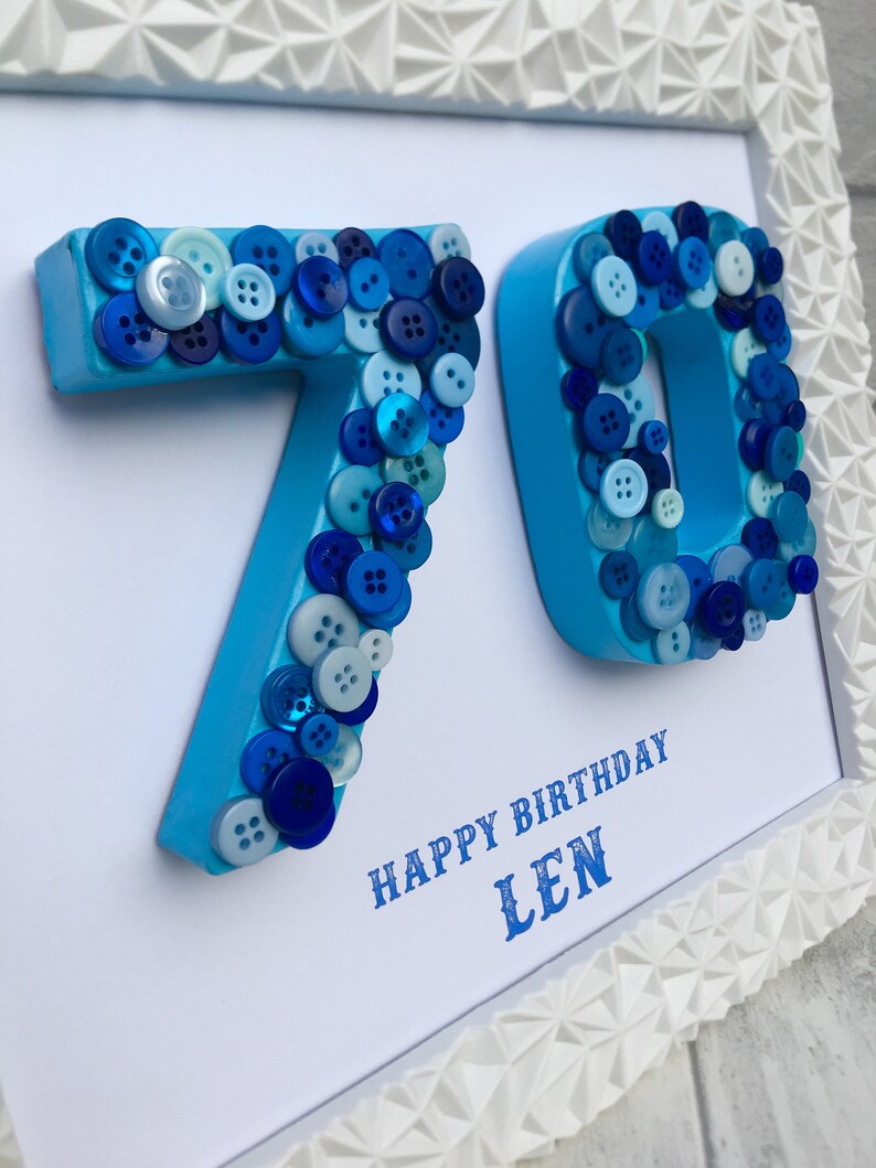 May include: A white framed picture with blue numbers 70 made of buttons. The text "Happy Birthday Len" is printed below the numbers.