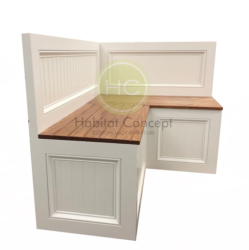 May include: White corner bench with a wood top and storage compartments. The bench has a white painted finish and a simple design. The bench is labeled "Habitat Concept Custom Made Furniture".