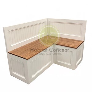 May include: White corner bench with a wood top and storage compartments. The bench has a white wainscot paneling design and the text "Habitat Concept Custom Made Furniture" is printed on the top.