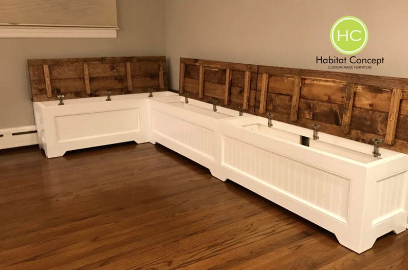 Puede incluir: Banco de esquina blanco con una tapa de madera que se levanta para revelar un espacio de almacenamiento. El banco est&aacute; hecho de madera y tiene un acabado pintado blanco. El banco est&aacute; en una habitaci&oacute;n con pisos de madera dura. El banco est&aacute; etiquetado como "Habitat Concept Muebles hechos a medida".
