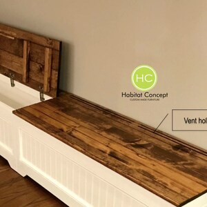 Puede incluir: Banco de almacenamiento blanco con una tapa de madera con bisagras y un respiradero. La tapa est&aacute; hecha de madera recuperada con un acabado r&uacute;stico. El banco est&aacute; etiquetado como "Habitat Concept Muebles hechos a medida".