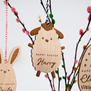 Op de afbeelding: Houten paaseieren ornament in de vorm van een schaap met de tekst "Happy Easter Harry" erop gegraveerd. Het ornament hangt aan een wit en zwart touwtje.