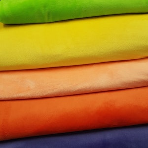 May include: A stack of colourful fabric rolls in shades of green, yellow, orange, red, and purple. The fabric is soft and plush, ideal for crafting or sewing projects.