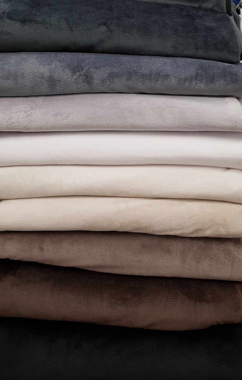 May include: A stack of fabric swatches in various shades of gray, beige, brown, and black. The fabric is soft and plush, with a velvety texture.