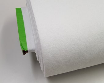 Pode incluir: Um rolo de tecido branco com fita verde na ponta.