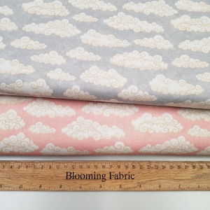 May include: Two fabric swatches with a white cloud pattern on a grey and pink background. The fabric is measured with a ruler that says "Blooming Fabric".