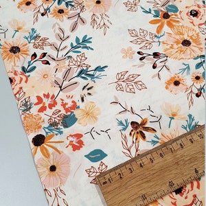 May include: White fabric with a floral print featuring orange, pink, and teal flowers. The fabric is shown with a ruler measuring 10 cm.
